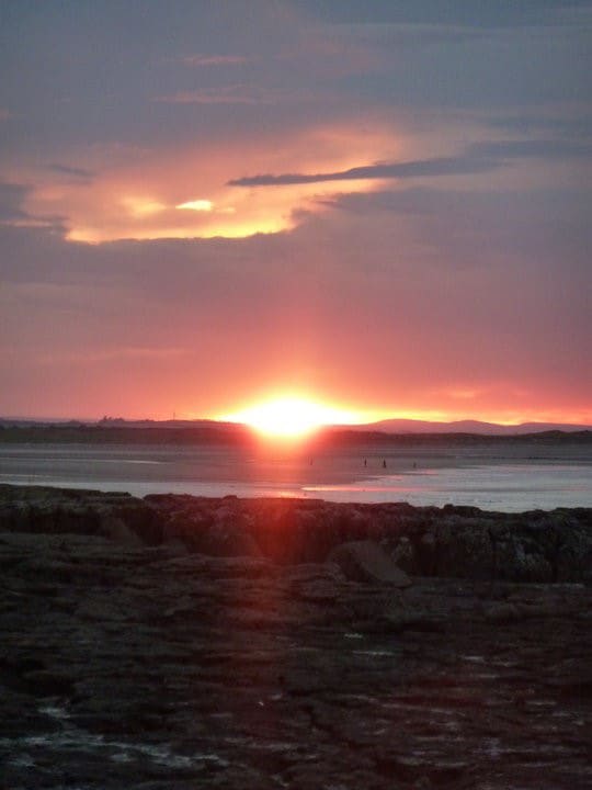 What is clinical hypnotherapy? The sun setting over the sea and a rocky shore
