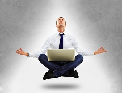 Deep relaxation A man in a suit meditating cross-legged, floating above the ground with a laptop