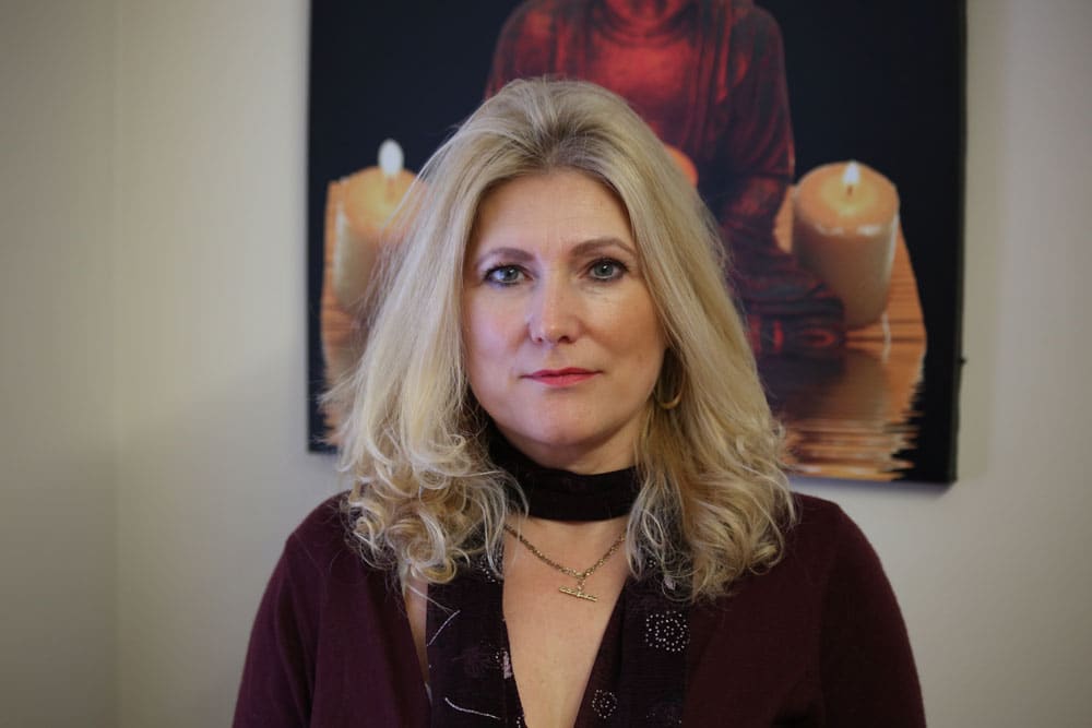 Sonya Hudson seated in front of a painting of candles