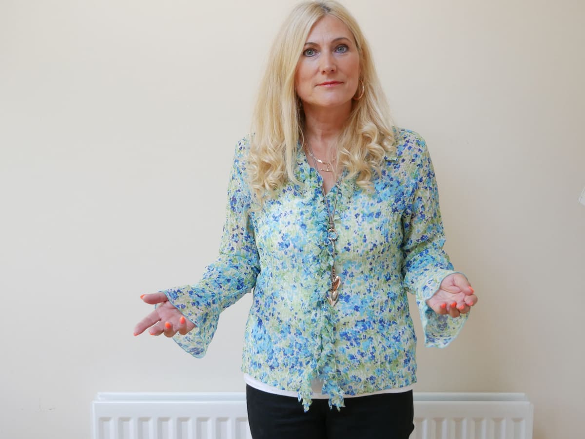 Sonya Hudson standing with open hands in a floral blouse