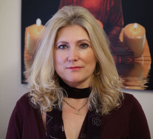 Sonya Hudson, Newcastle hypnotherapist Head-and-shoulders portrait of Sonya Hudson in front of a candle painting